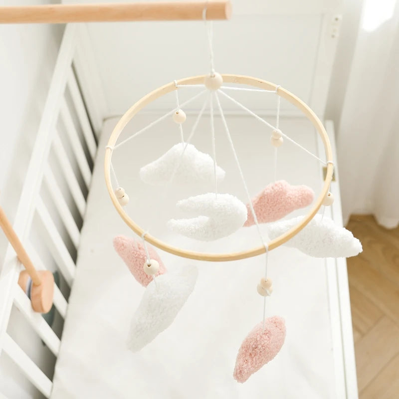 Baby mobile with white and pink plush toys hanging from a crib
