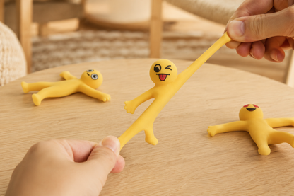 Yellow Stretchy Buddies™ sensory toy being stretched by hand on wooden table for stress relief and screen-free play