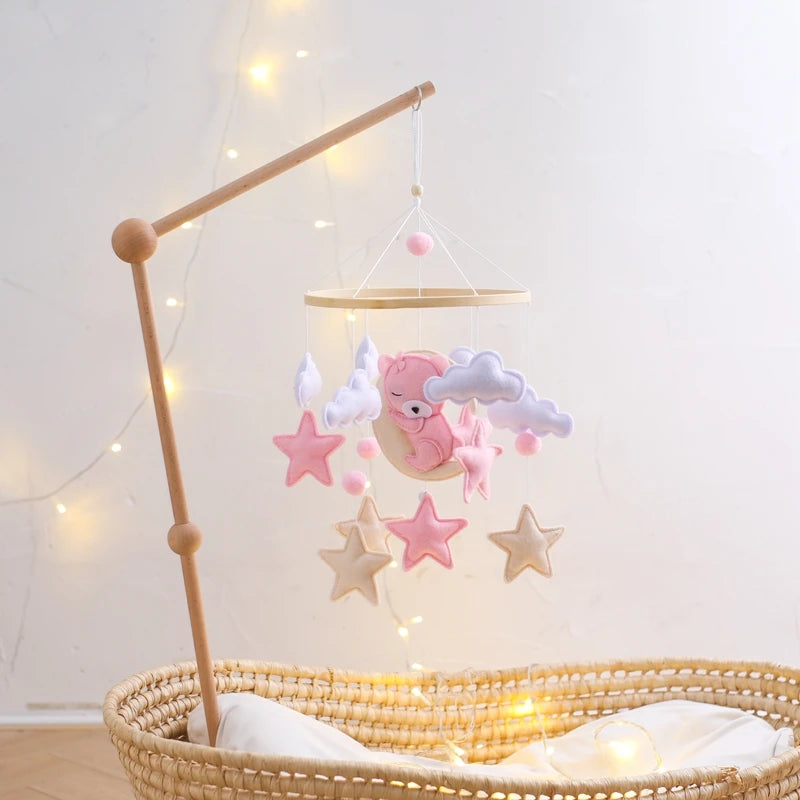 Baby crib mobile with stars and a bear hanging above a crib with fairy lights.