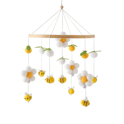 Children's mobile with flowers and bees hanging from a wooden rod on a white background