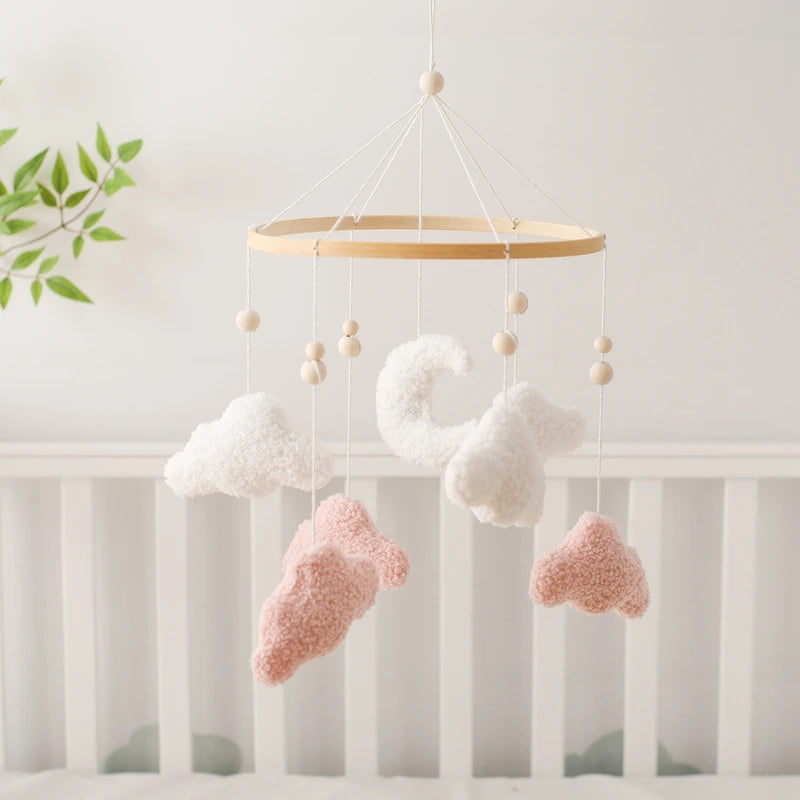 Baby crib mobile with cloud and heart shapes hanging above a crib.