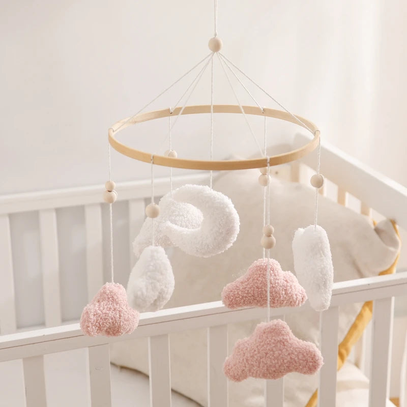 Baby crib mobile with cloud-shaped decorations hanging over a crib.