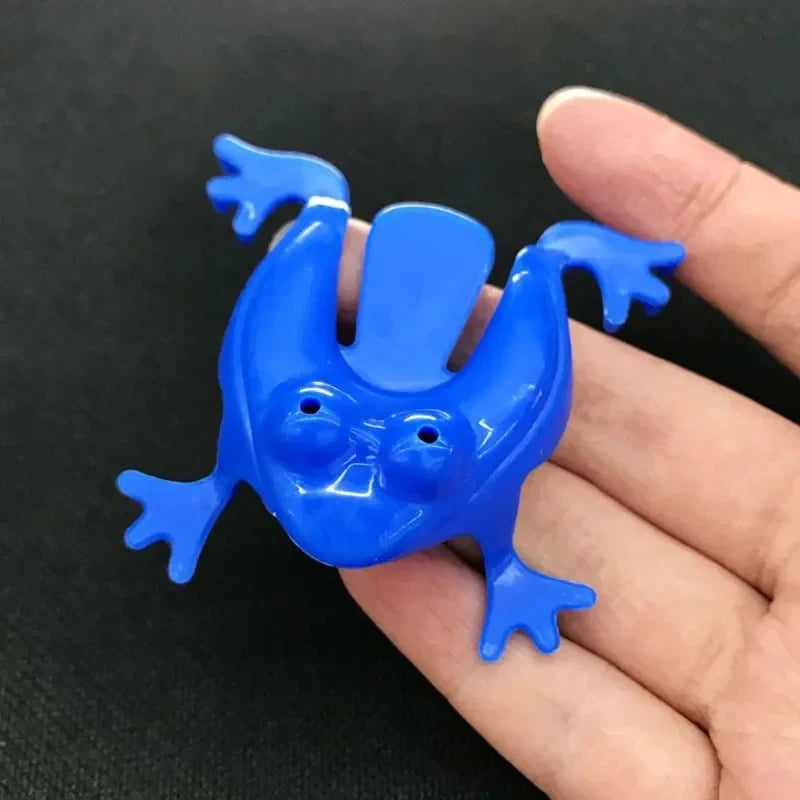 Blue plastic frog-shaped object held in a hand against a black background