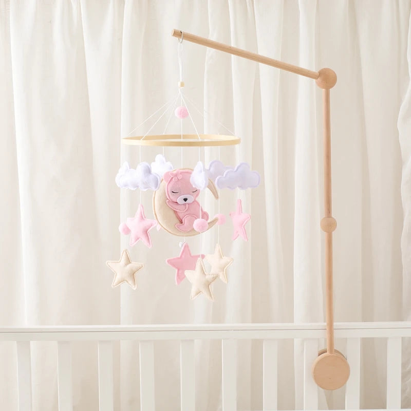 Baby crib mobile with teddy bear and stars against a white curtain background