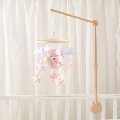 Baby crib mobile with teddy bear and stars against a white curtain background