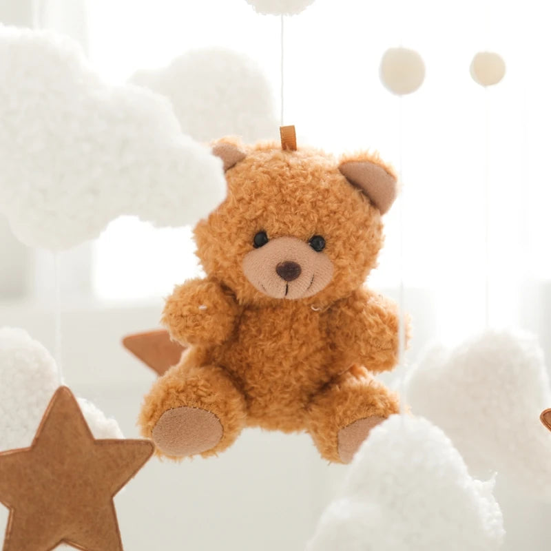Brown teddy bear hanging against a soft, neutral background with stars and circles.
