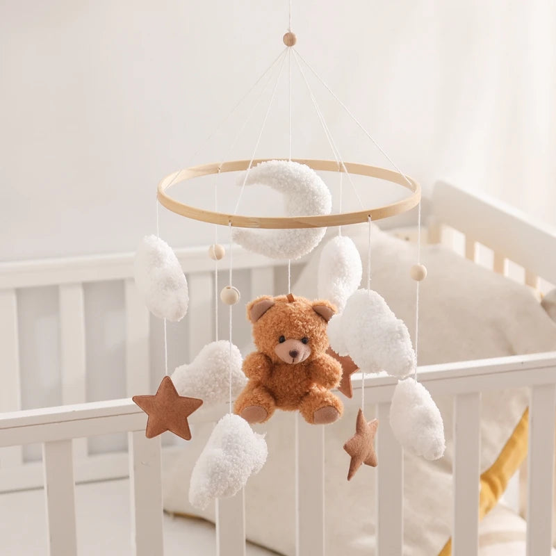 Baby crib with a mobile featuring a teddy bear, stars, and clouds.