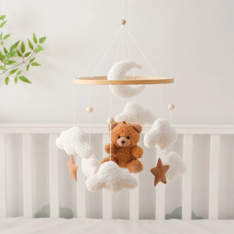 Baby crib mobile with teddy bear, clouds, and stars hanging above a crib.