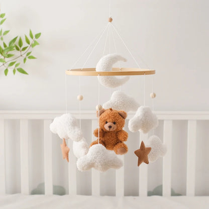 Baby crib mobile with teddy bear, clouds, and stars hanging above a crib.