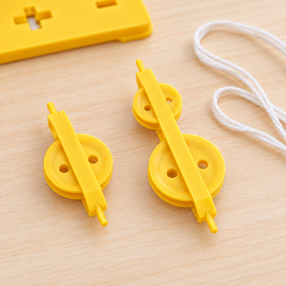 Close-up of yellow single and double pulley units on a wooden table, with white cord alongside and part of the support base in the background.