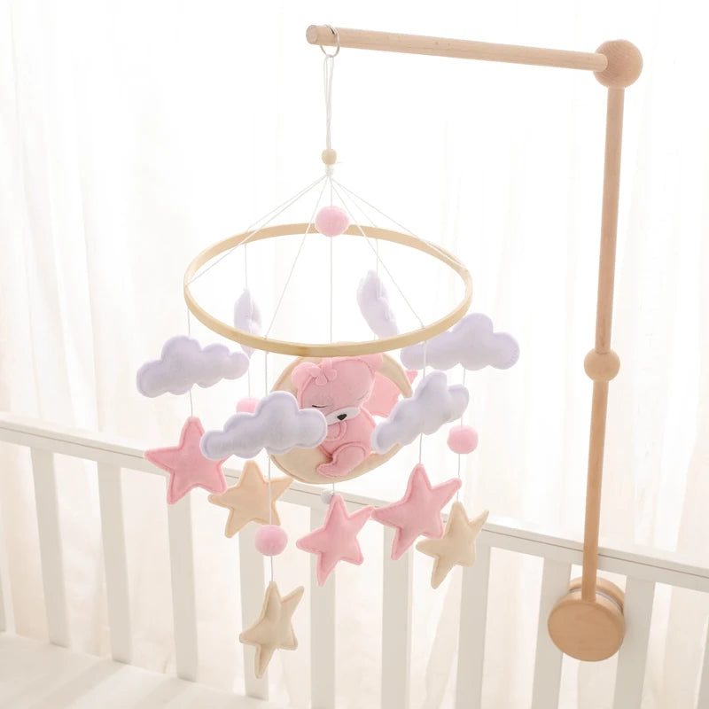 Baby crib mobile with teddy bear, stars, and clouds hanging from a wooden stand.