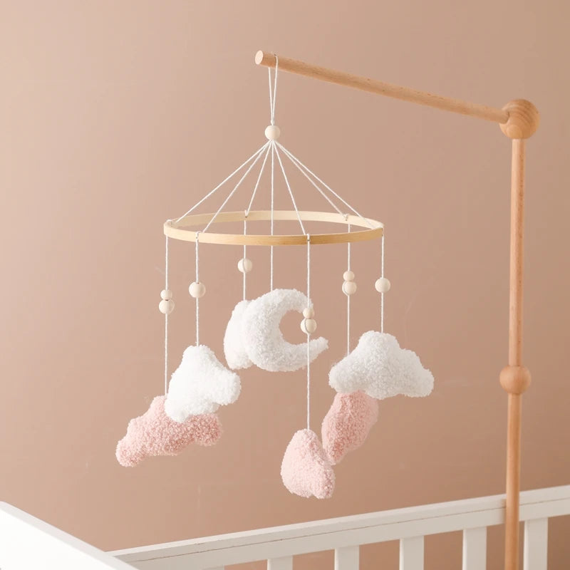 Baby mobile with clouds and stars hanging above a crib against a beige wall.