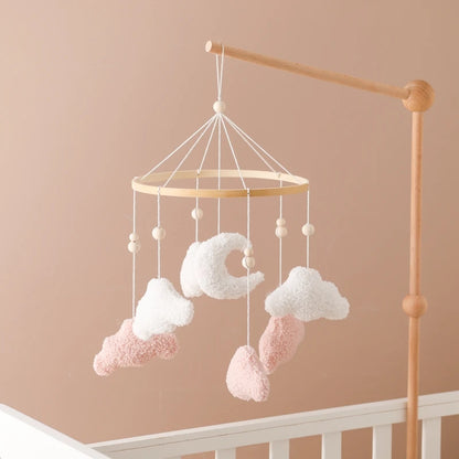 Baby mobile with clouds and stars hanging above a crib against a beige wall.
