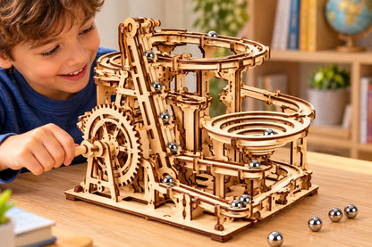 Young builder turning the hand crank on a wooden mechanical marble run