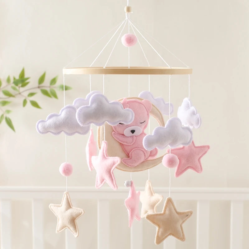 Baby mobile with pink bear, clouds, and stars hanging against a light background