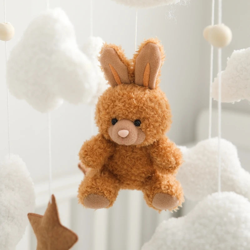 Brown teddy bear with bunny ears hanging among white clouds and stars.
