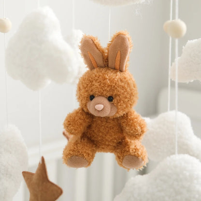 Brown teddy bear with bunny ears hanging among white clouds and stars.
